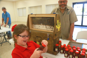 A girl visiting the Brazoria County Beekeepers Booth checks out a bottle of honey at the Keep Pearland Beautiful Gardening Expo on August 27, 2015.